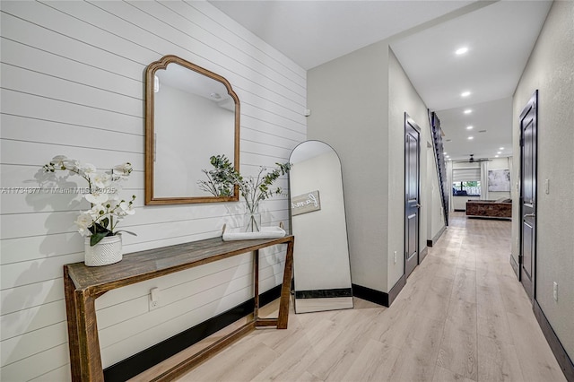 hallway with wooden walls and light hardwood / wood-style flooring