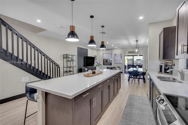 kitchen featuring a kitchen island, sink, dark brown cabinets, and light wood-type flooring