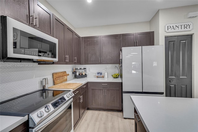 kitchen with white refrigerator, dark brown cabinetry, tasteful backsplash, and electric range