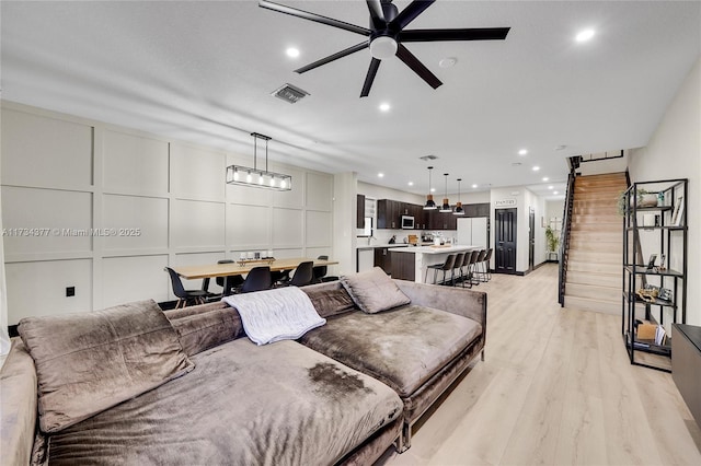 living room with ceiling fan, a barn door, and light wood-type flooring