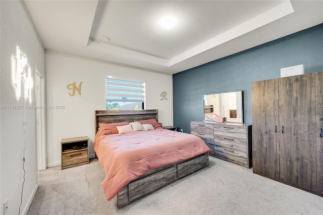 bedroom featuring light colored carpet and a raised ceiling