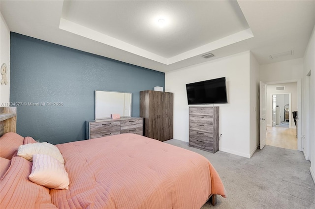 carpeted bedroom with a raised ceiling