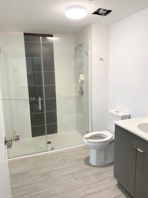 bathroom featuring vanity, toilet, and a shower with shower door