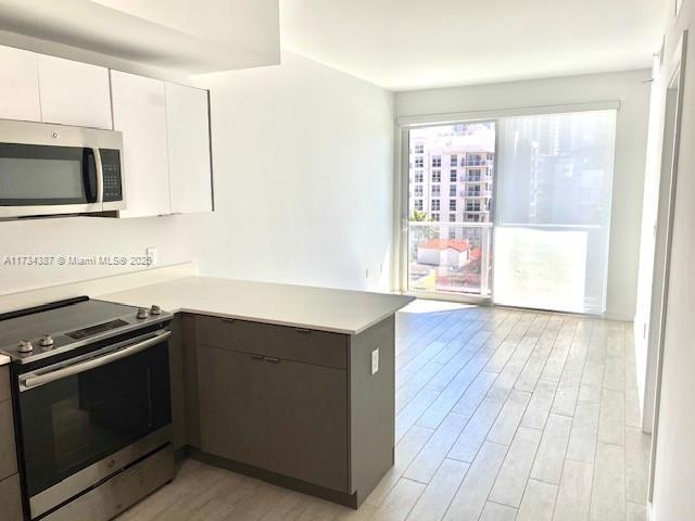 kitchen featuring white cabinetry, appliances with stainless steel finishes, kitchen peninsula, and light hardwood / wood-style flooring