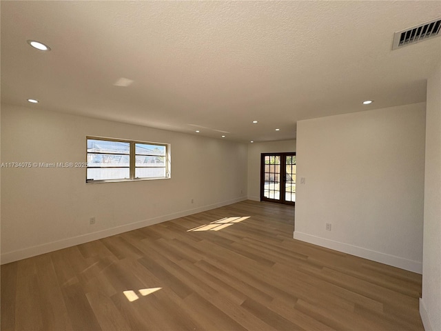 empty room featuring hardwood / wood-style flooring, french doors, and a healthy amount of sunlight