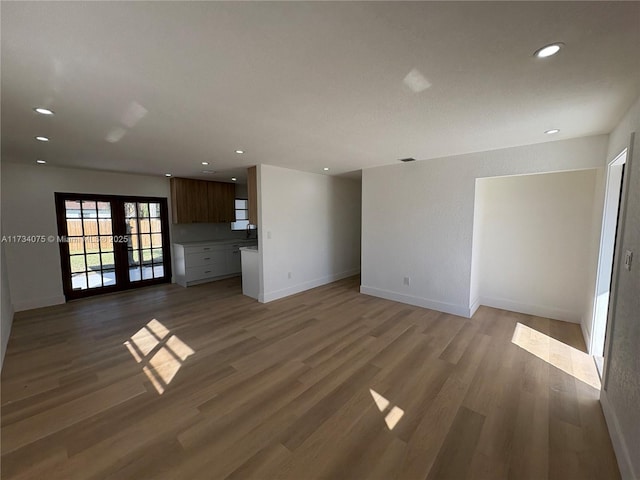 unfurnished living room featuring hardwood / wood-style floors and french doors