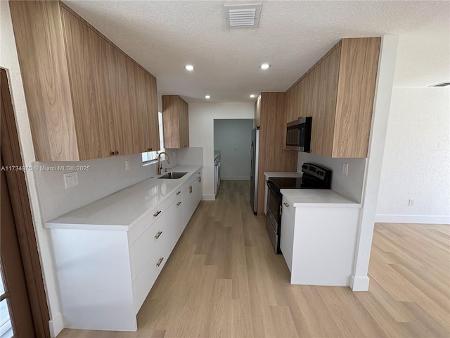 kitchen with white cabinetry, stainless steel appliances, sink, and a textured ceiling