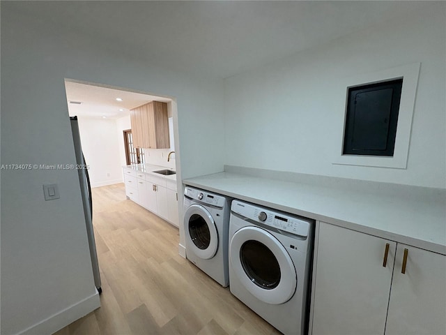 laundry area with cabinets, sink, washing machine and dryer, and light hardwood / wood-style floors