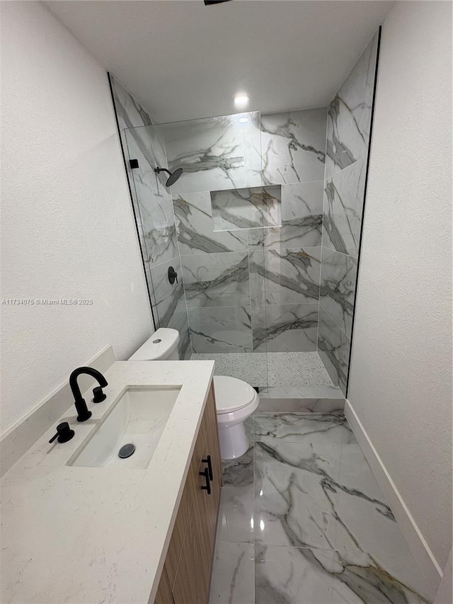 bathroom featuring vanity, tiled shower, and toilet