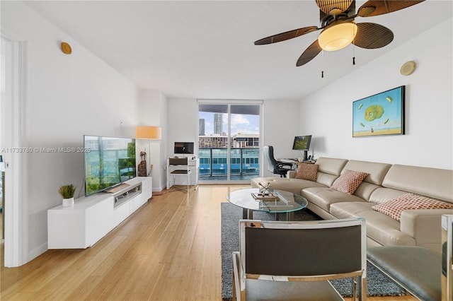 living room with expansive windows, ceiling fan, and light wood-type flooring