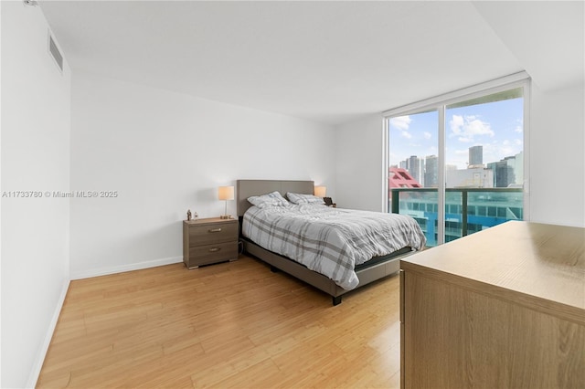 bedroom with expansive windows and light hardwood / wood-style floors