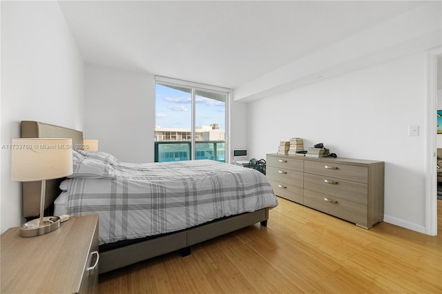 bedroom featuring floor to ceiling windows, access to exterior, and light hardwood / wood-style flooring