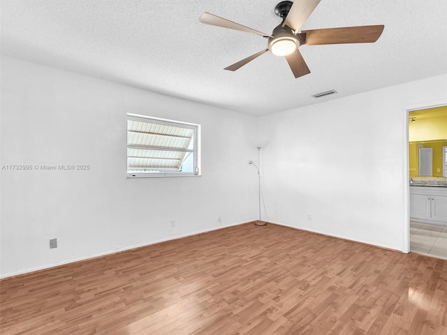 unfurnished room with ceiling fan, light hardwood / wood-style floors, and a textured ceiling