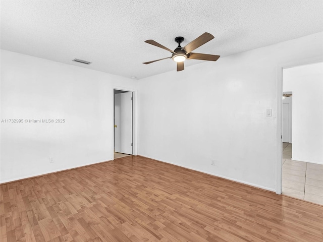 unfurnished room with ceiling fan, a textured ceiling, and light wood-type flooring