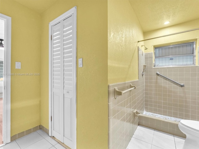 bathroom featuring tiled shower, tile patterned floors, a textured ceiling, and toilet