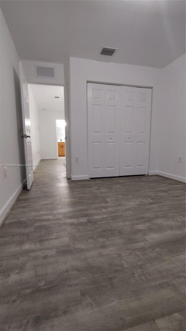 unfurnished bedroom with dark hardwood / wood-style flooring and a closet