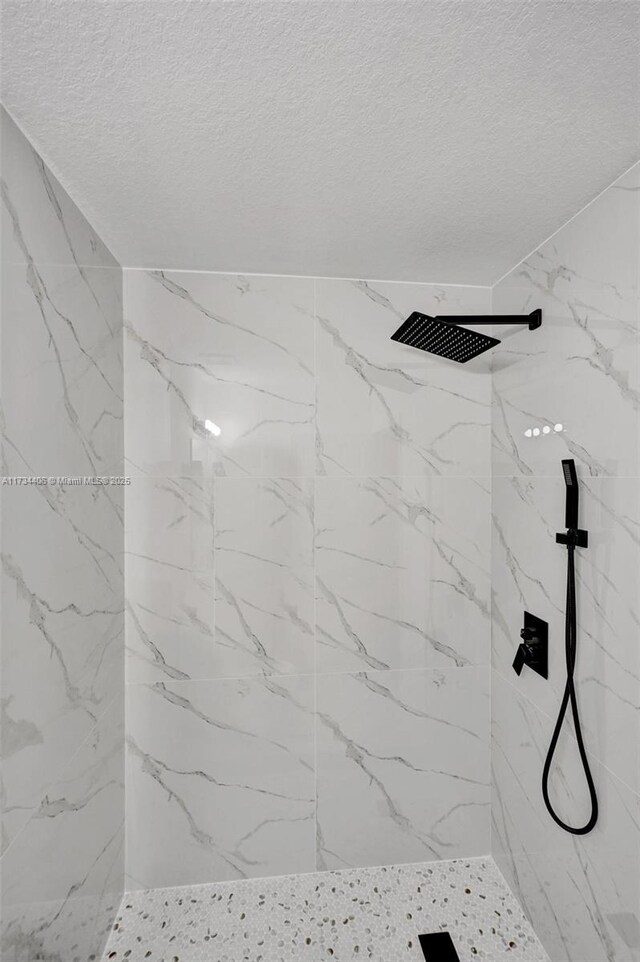 bathroom featuring a textured ceiling, toilet, and tiled shower