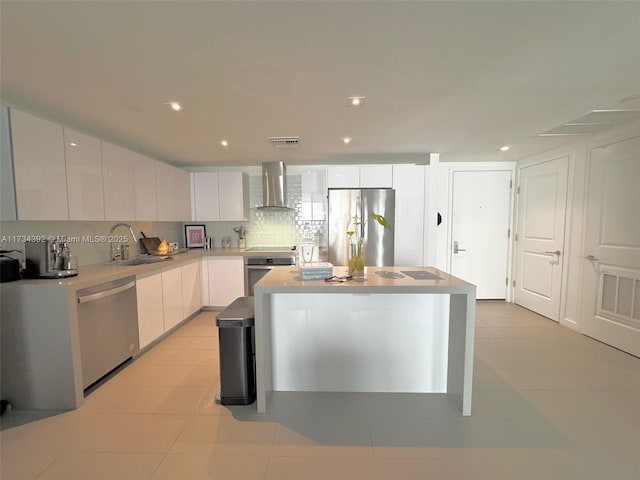 kitchen with light tile patterned flooring, appliances with stainless steel finishes, white cabinets, backsplash, and wall chimney range hood