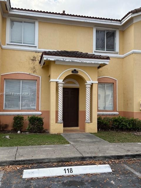 entrance to property with a tile roof and stucco siding