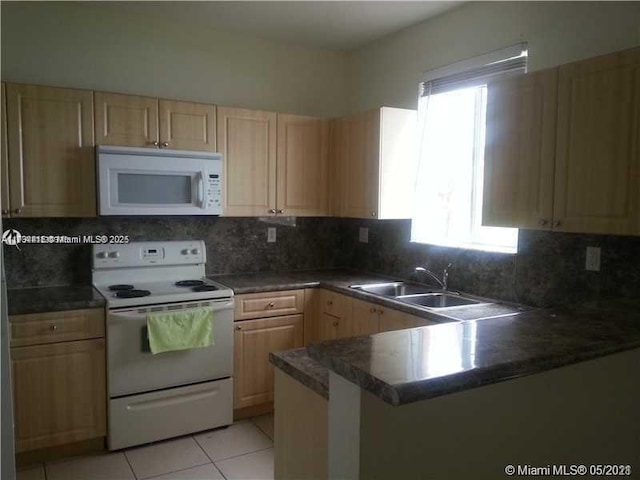 kitchen featuring kitchen peninsula, sink, white appliances, light tile patterned floors, and decorative backsplash