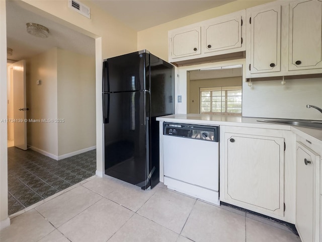 kitchen with white dishwasher, sink, black refrigerator, and white cabinets