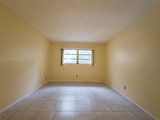 empty room with light tile patterned flooring and a textured ceiling