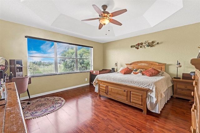 bedroom featuring dark wood-type flooring, ceiling fan, and a raised ceiling