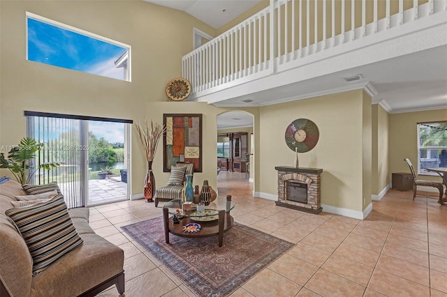 living room featuring light tile patterned flooring, ornamental molding, a fireplace, and a high ceiling