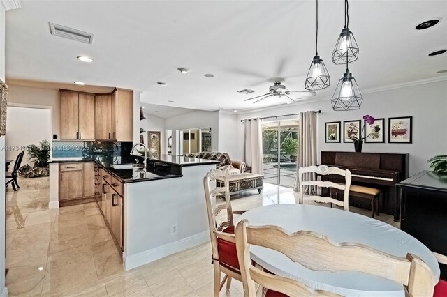 kitchen with sink, decorative light fixtures, kitchen peninsula, ceiling fan, and decorative backsplash