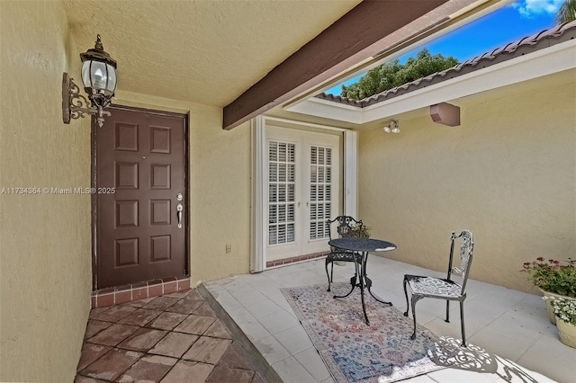 view of exterior entry featuring french doors and a patio