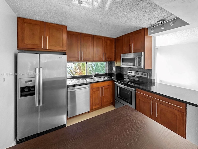 kitchen with stainless steel appliances, rail lighting, sink, and a textured ceiling