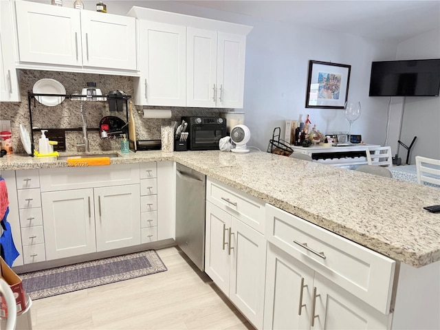 kitchen with white cabinetry, dishwasher, decorative backsplash, light stone countertops, and light hardwood / wood-style flooring