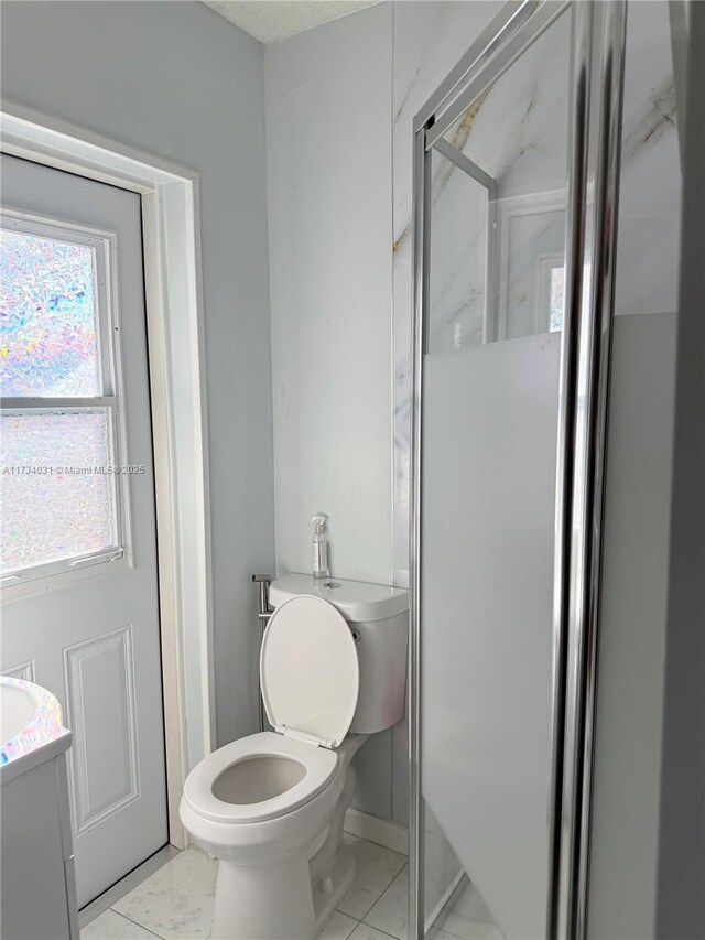 bathroom with an enclosed shower, vanity, tile patterned floors, and toilet