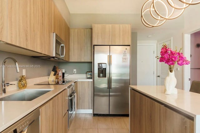 kitchen with hanging light fixtures, appliances with stainless steel finishes, sink, and light tile patterned floors