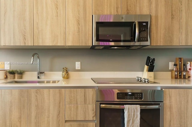 kitchen with appliances with stainless steel finishes, sink, and light brown cabinets