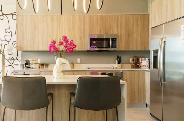 kitchen featuring appliances with stainless steel finishes, a breakfast bar, and light brown cabinets