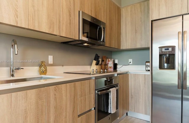 kitchen with appliances with stainless steel finishes, sink, and light brown cabinets