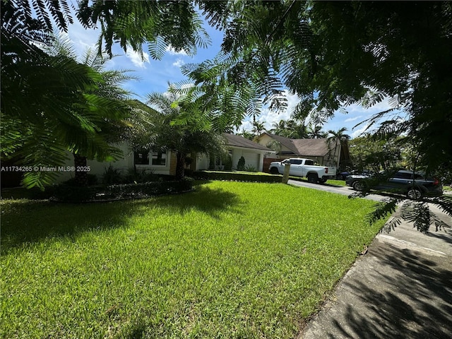 view of front of house featuring driveway, an attached garage, and a front lawn