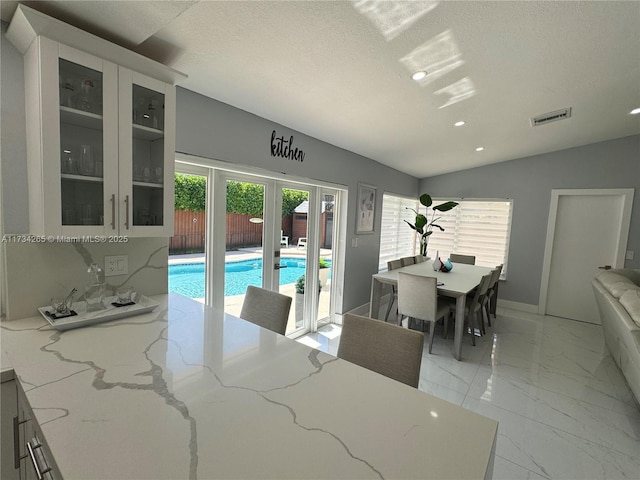 dining space featuring visible vents, marble finish floor, a textured ceiling, french doors, and vaulted ceiling