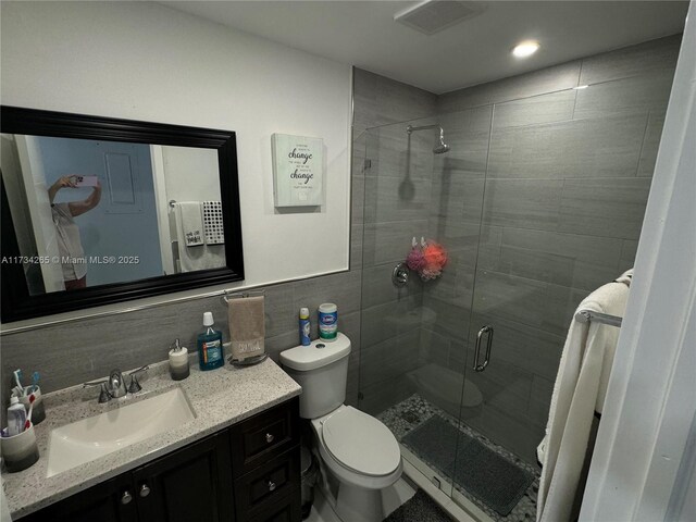 full bath featuring visible vents, toilet, tile walls, a shower stall, and vanity