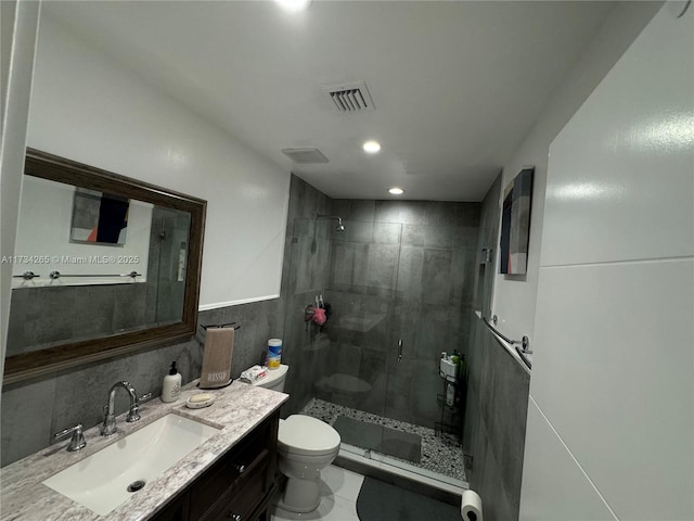 bathroom featuring visible vents, a shower stall, toilet, wainscoting, and vanity