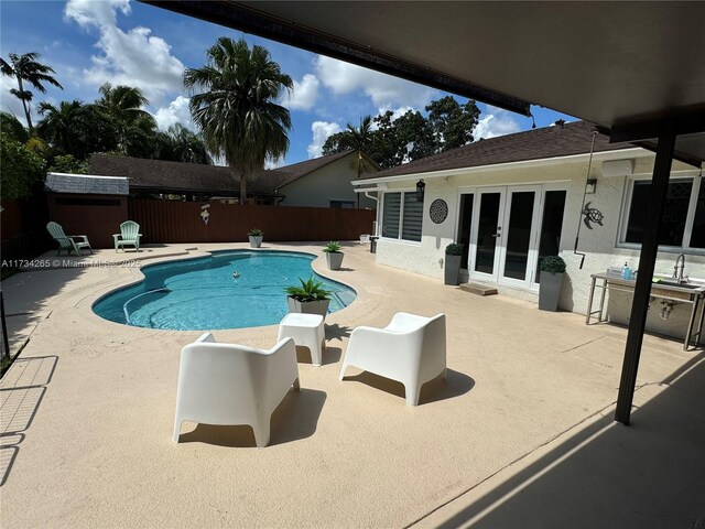 view of pool featuring french doors, fence, a fenced in pool, and a patio area