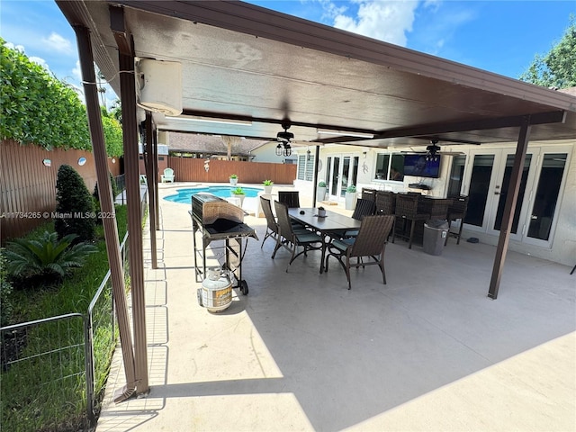 view of patio featuring outdoor dining space, a ceiling fan, a fenced backyard, french doors, and a fenced in pool