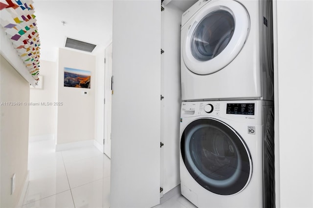 clothes washing area with light tile patterned flooring and stacked washer / dryer