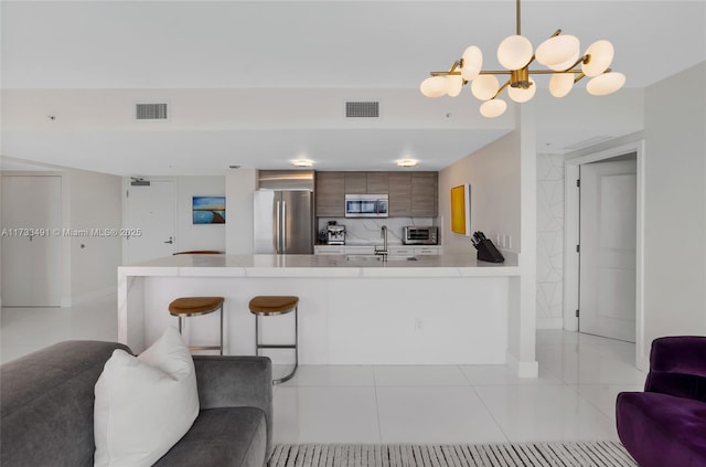 kitchen with light tile patterned flooring, a kitchen bar, hanging light fixtures, kitchen peninsula, and stainless steel appliances