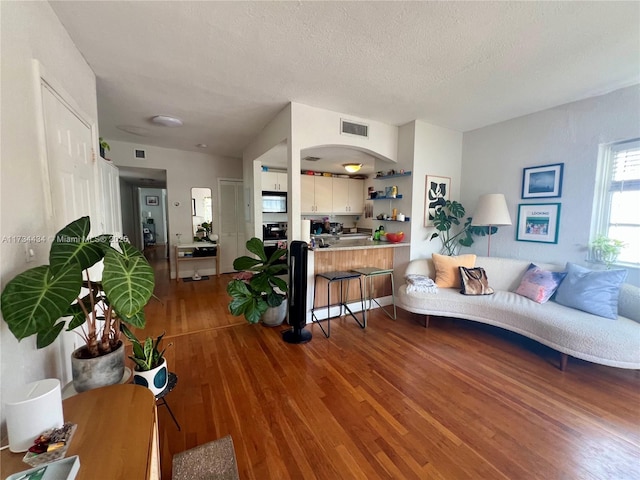 living room featuring wood-type flooring and a textured ceiling