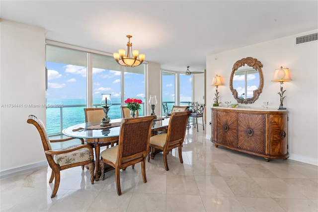 dining space with a water view, expansive windows, and ceiling fan with notable chandelier