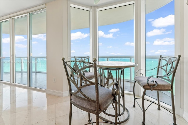 tiled dining area featuring a water view and a wall of windows