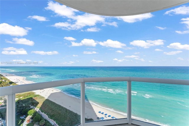 balcony with a water view and a view of the beach