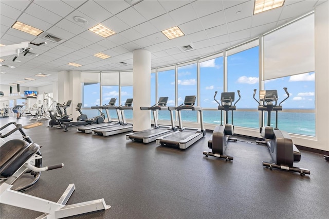 exercise room featuring a paneled ceiling and a water view